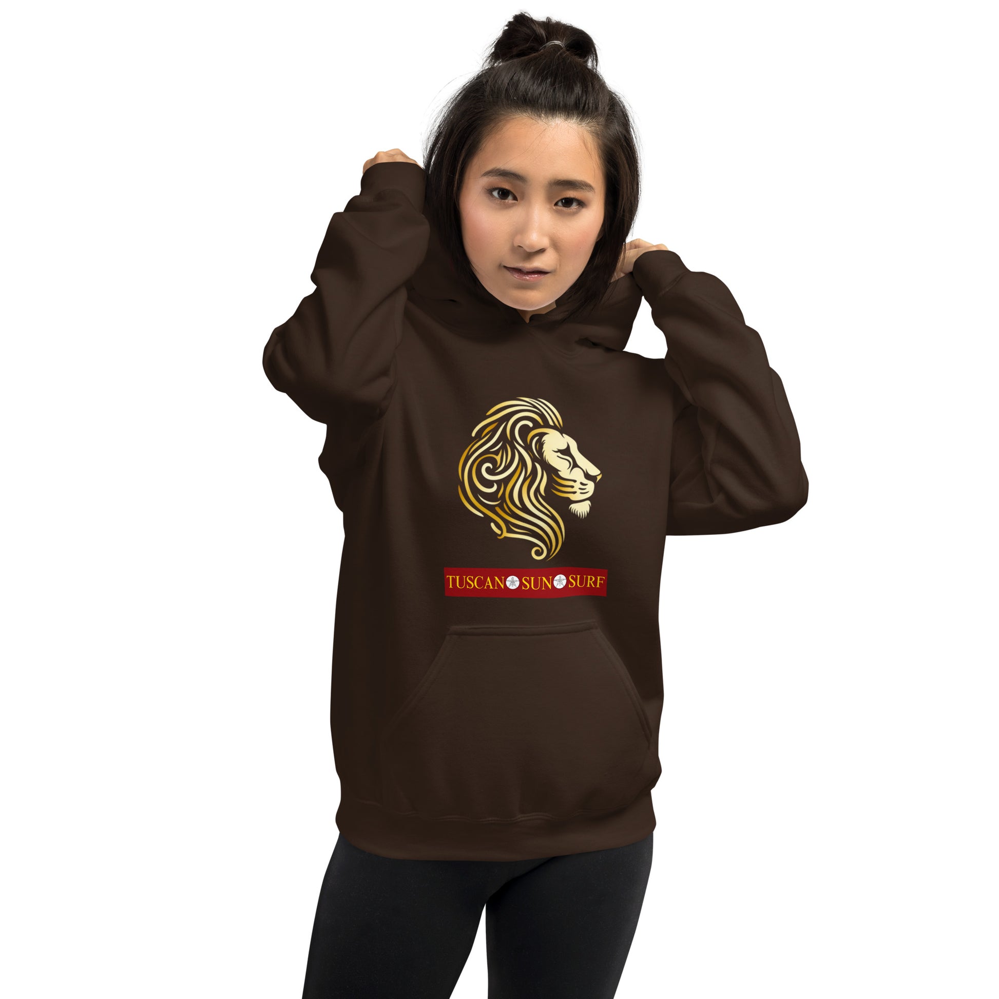 Woman wearing a unisex dark chocolate brown hoodie with a lion head in shades of yellow. Below the lion face is the Tuscan Sun Surf logo.