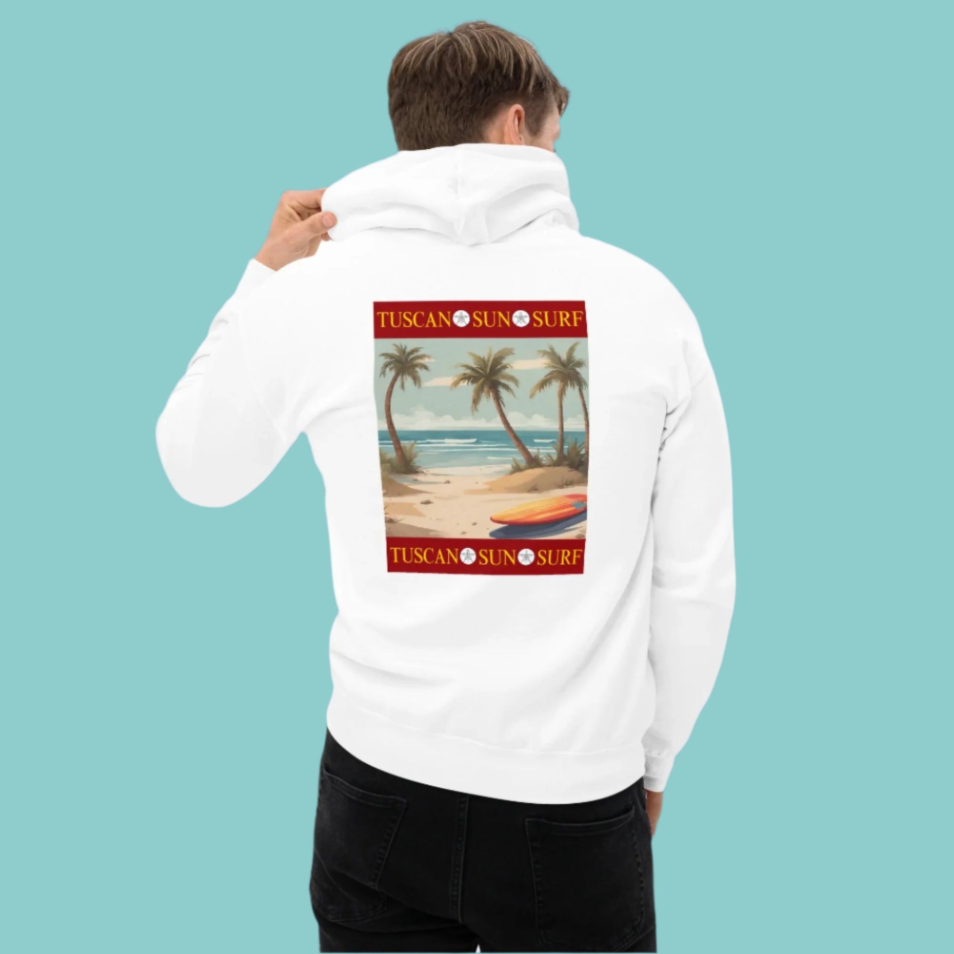 Back of a man wearing a white unisex hoodie with a graphic design of a beach with palm trees and an orange and yellow surf board. The Tuscan Sun Surf logo borders above and below the design